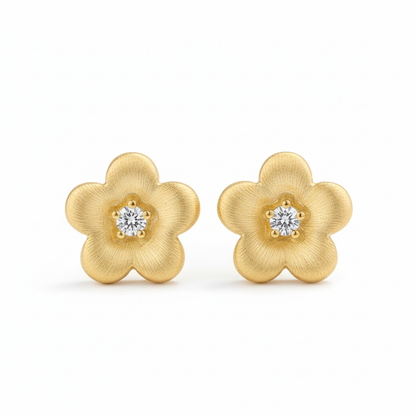 Gold brushed flower stud earrings on white background
