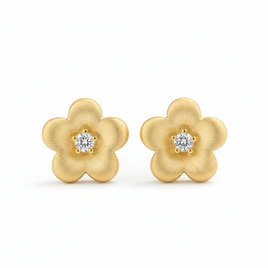 Gold brushed flower stud earrings on white background