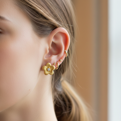 Gold brushed flower stud earrings styled with other earrings
